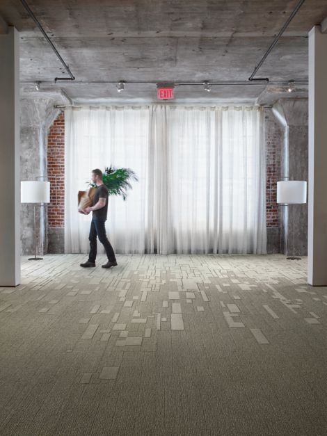 Interface EM551 and EM553 plank carpet tile in open office with man carrying a plant