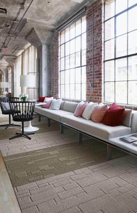 Interface EM552 and EM553 plank carpet tile in open area with brick wall and white couches