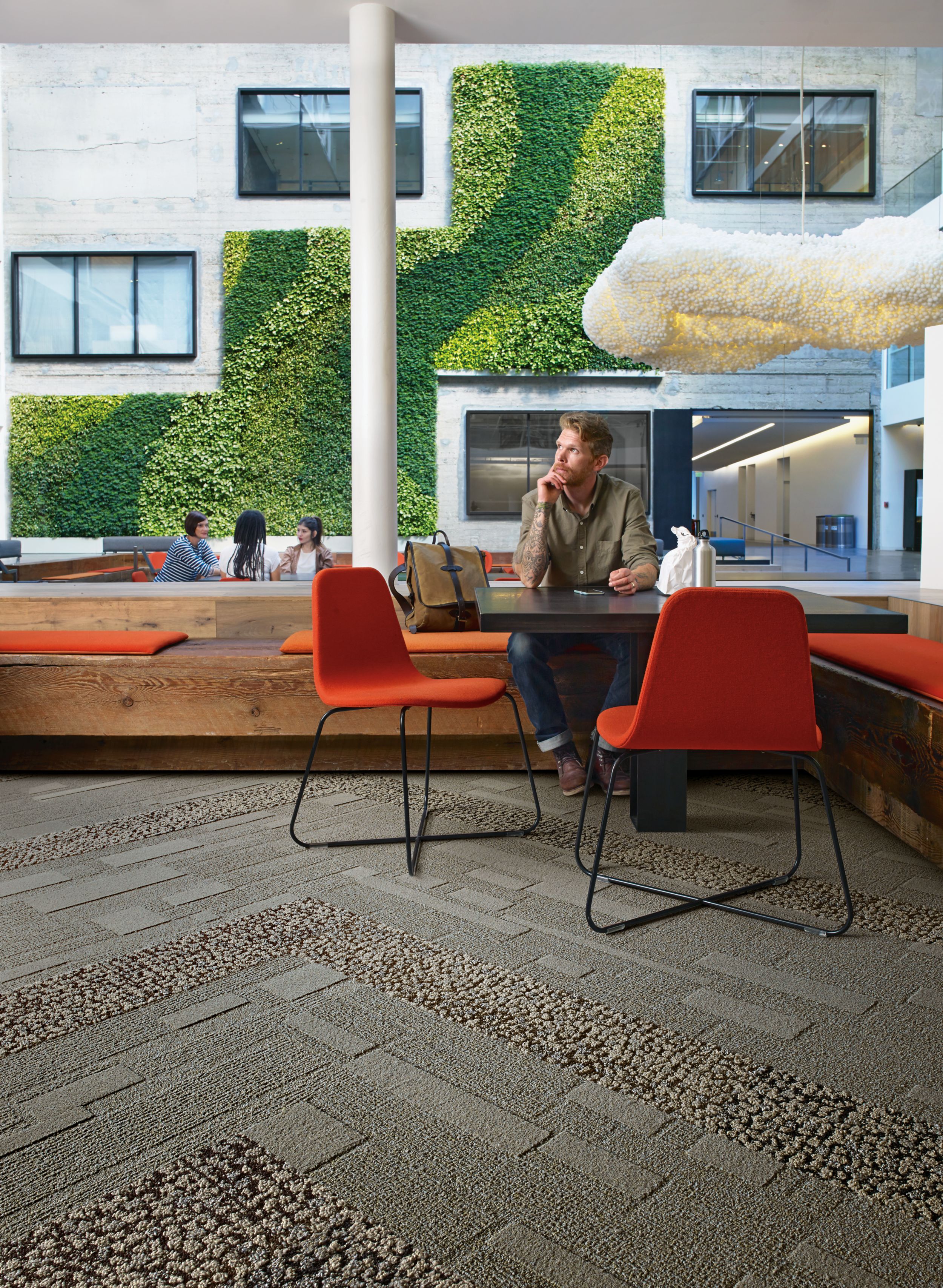 Interface EM552 plank carpet tile with man sitting at table with lunch and group meeting in front of vine wall in the background  afbeeldingnummer 7