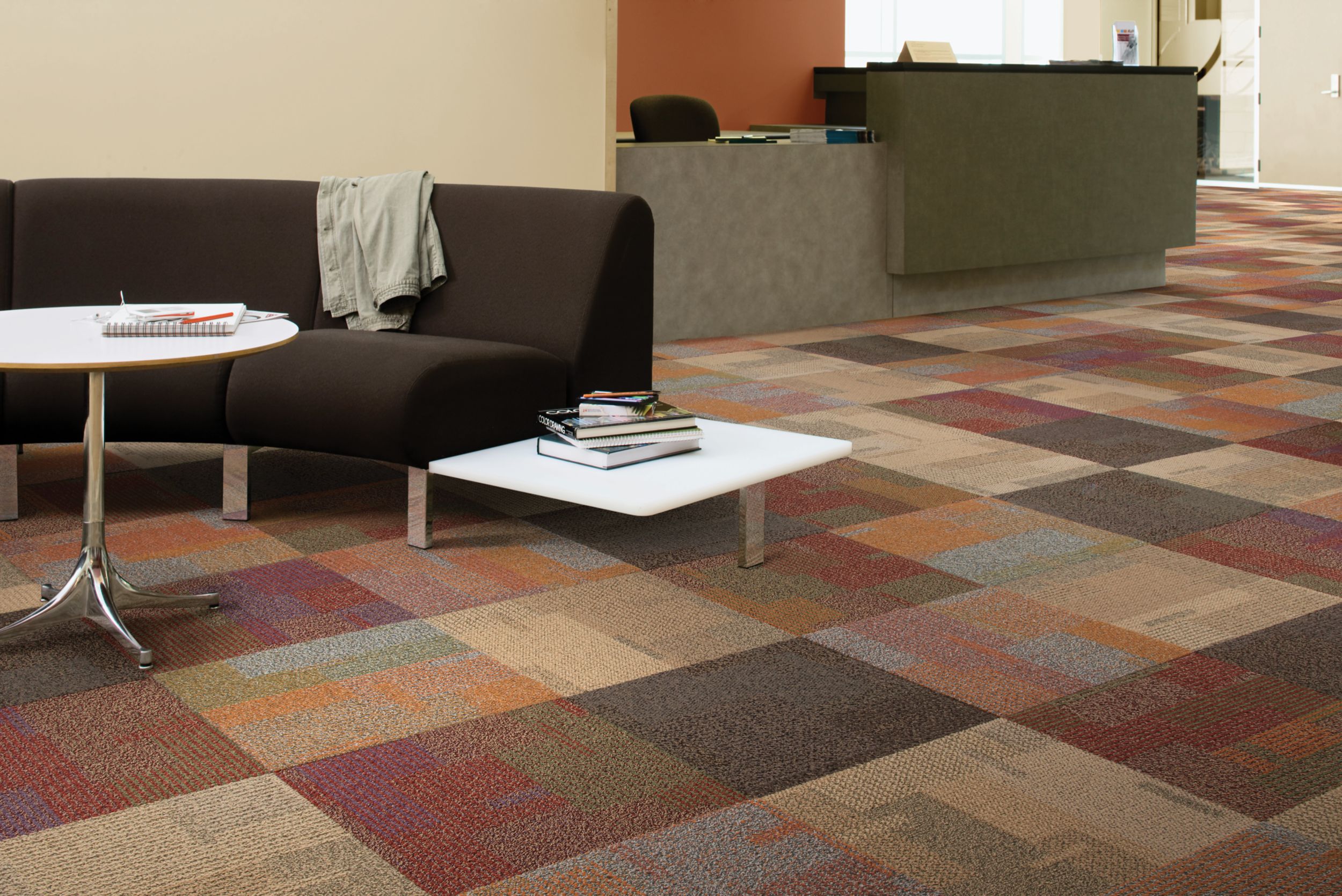 Interface Entropy carpet tile in front desk waiting area with books and notepad on table and black couch image number 3