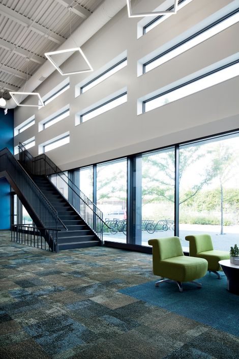 Interface Exposed carpet tile in open space with open stairway and bikes in the background outside