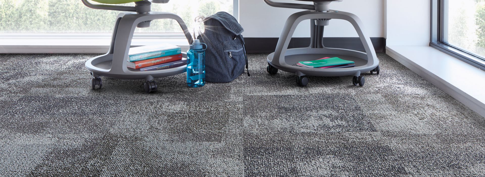 Interface Exposed carpet tile in corner with green and black school desks and horizontal windowns