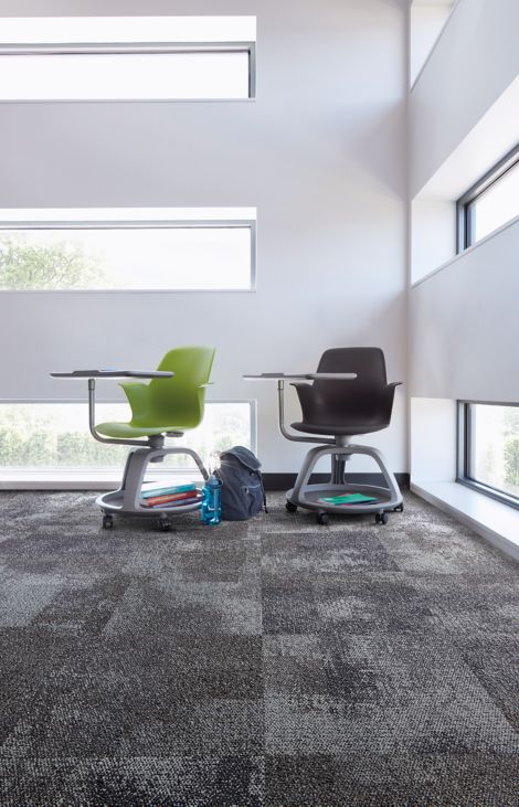Interface Exposed carpet tile in corner with green and black school desks and horizontal windowns