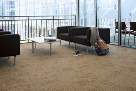 Interface Syncopation carpet tile in seating area with four chairs, short glass table, backpack and jacket