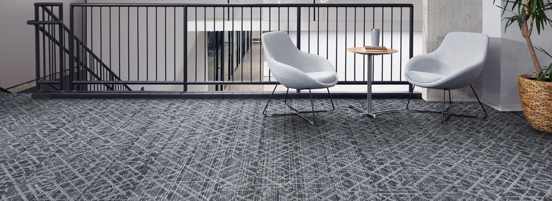 Interface Glisten plank carpet tile in seating area at stairwell with white chairs, small table and plant