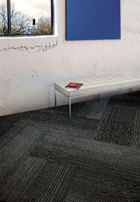 Interface Grasmere plank carpet tile against white wall and white bench 