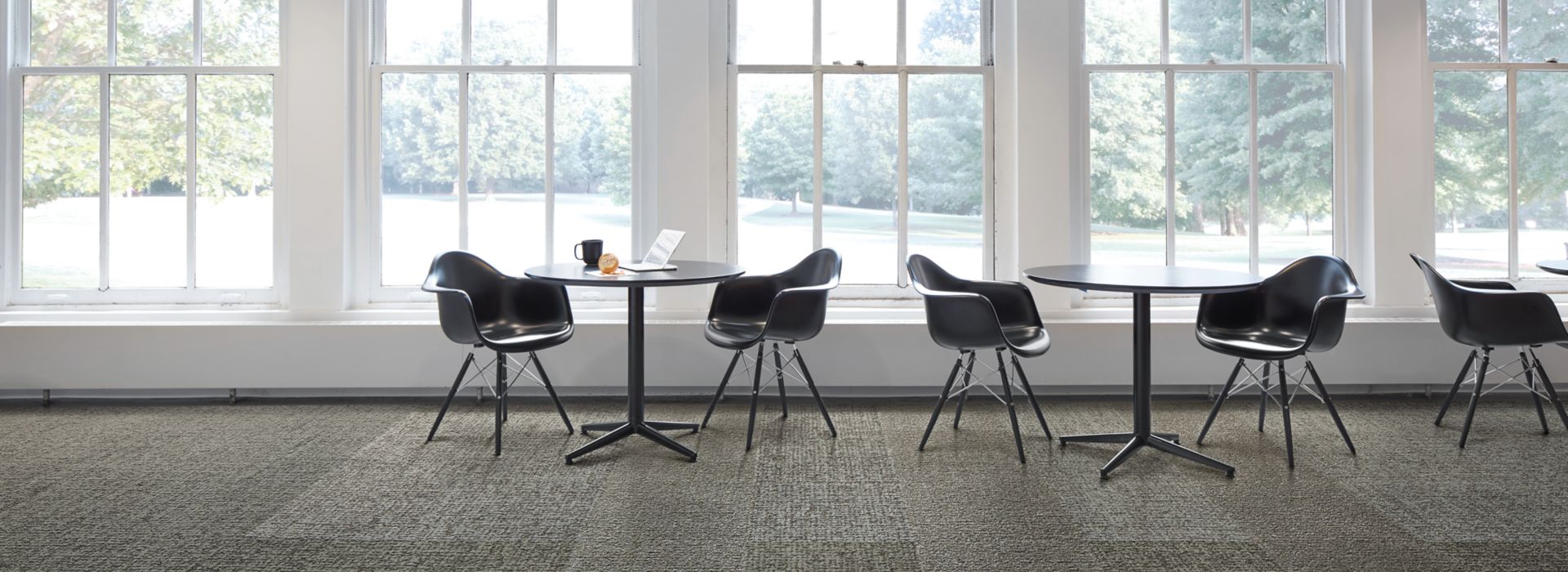 Interface Gridlock carpet tile with small tables against a wall of windows imagen número 1