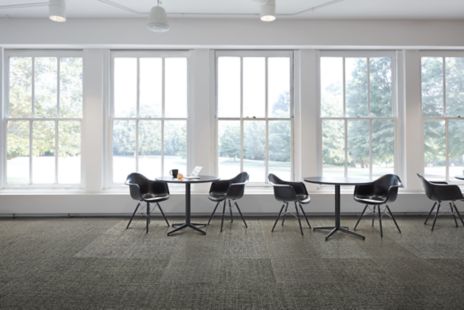 Interface Gridlock carpet tile with small tables against a wall of windows imagen número 1