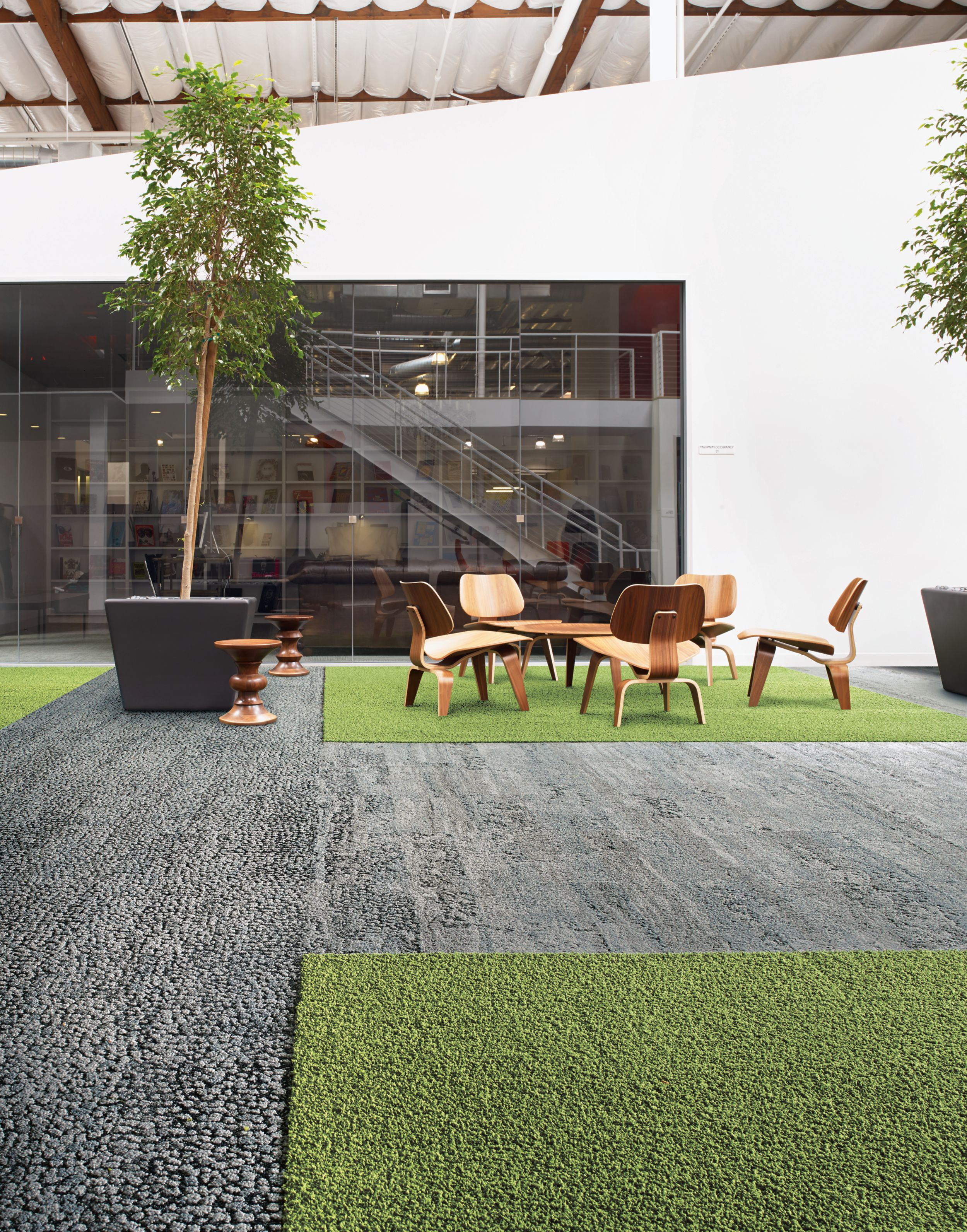 Interface HN810, HN830, HN840 and HN850 plank carpet tiles in open area with wood table and chairs and stairwell in the background image number 9