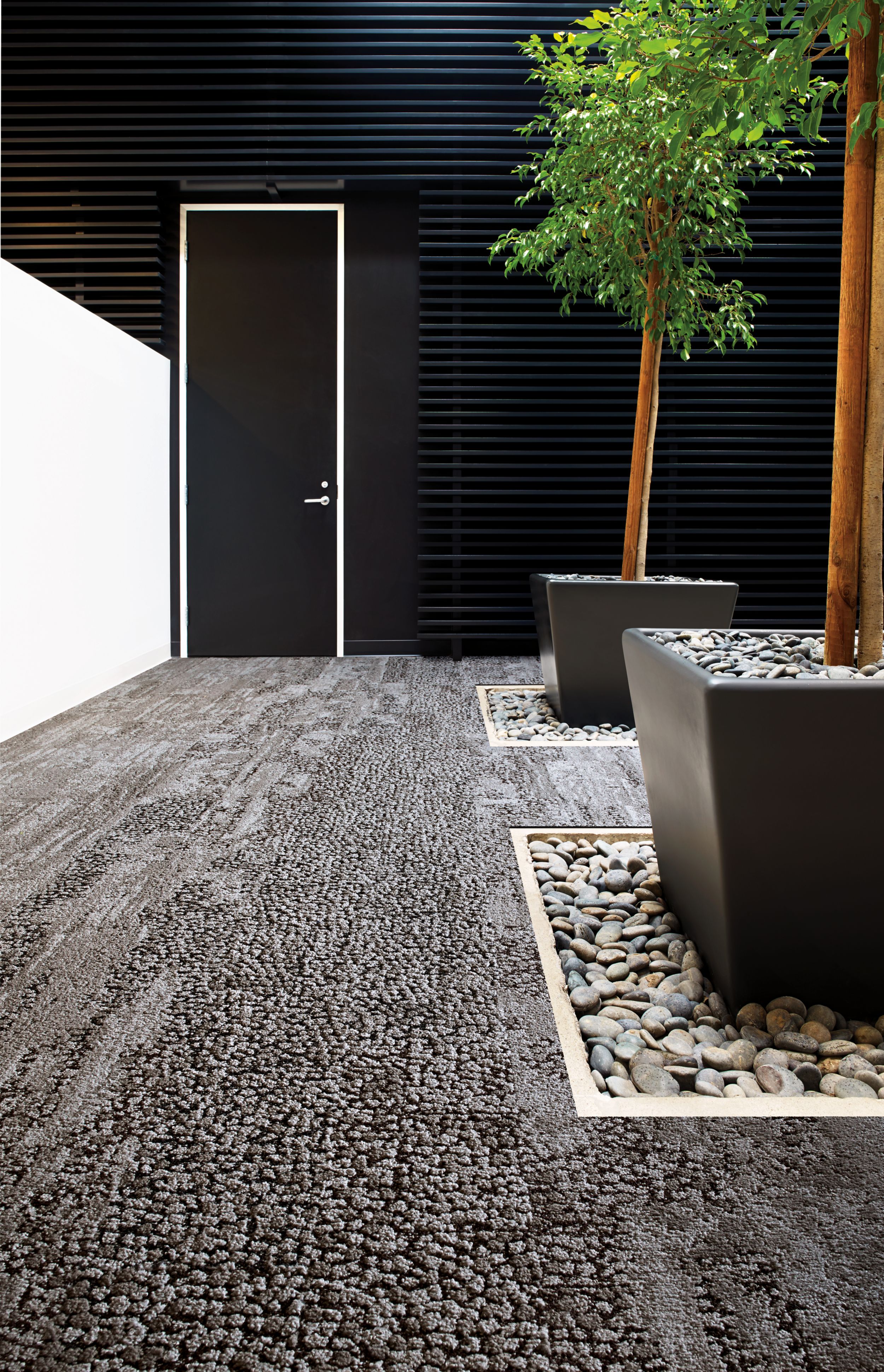 Interface HN810, HN820, HN840 and HN850 plank carpet tiles in white anc black room with potted trees and river rock número de imagen 5