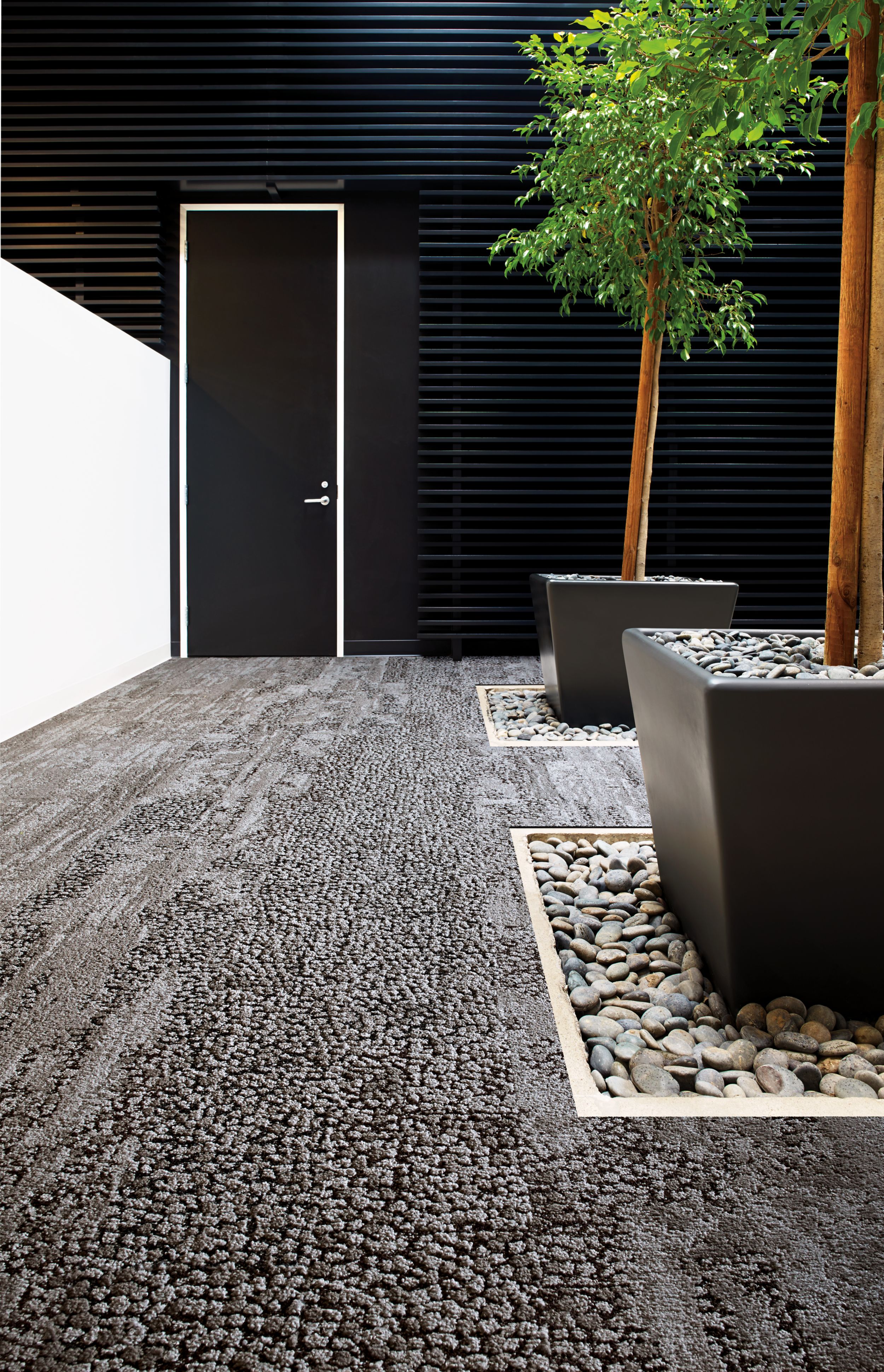 Interface HN810, HN820, HN840 and HN850 plank carpet tiles in white anc black room with potted trees and river rock número de imagen 4