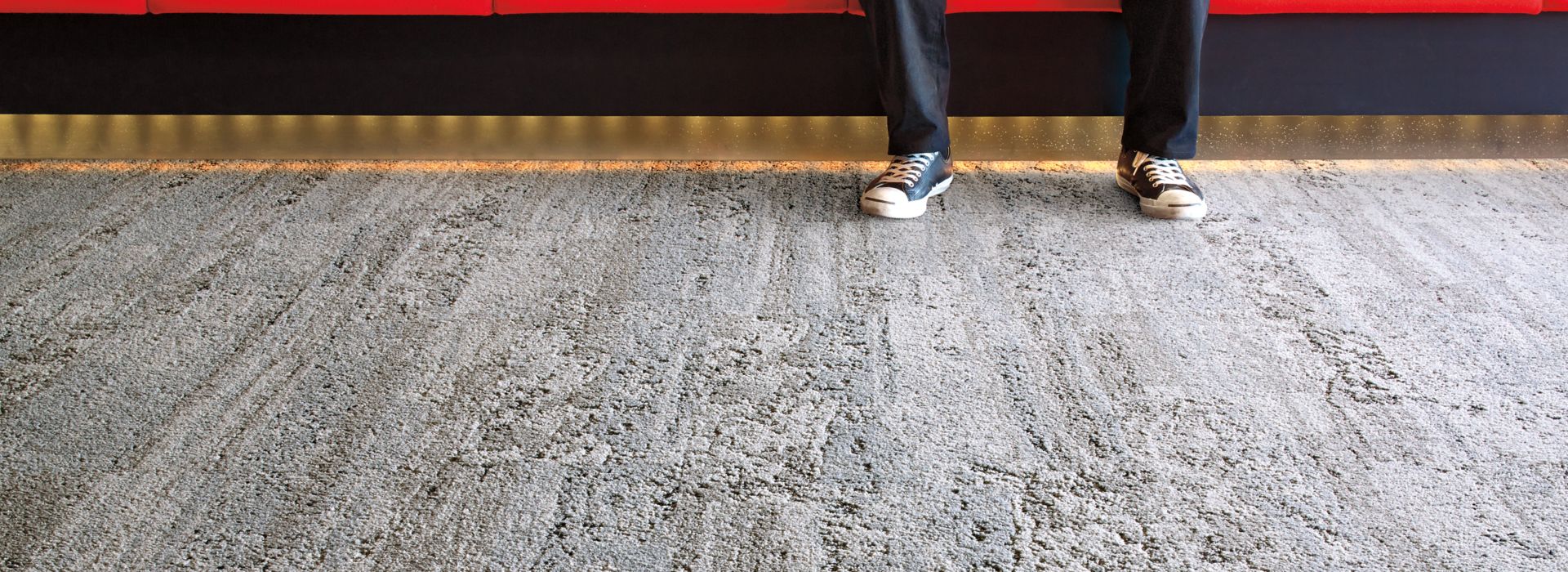 Interface HN810 plank carpet tile in waiting area with red bench and wall and man listening to music