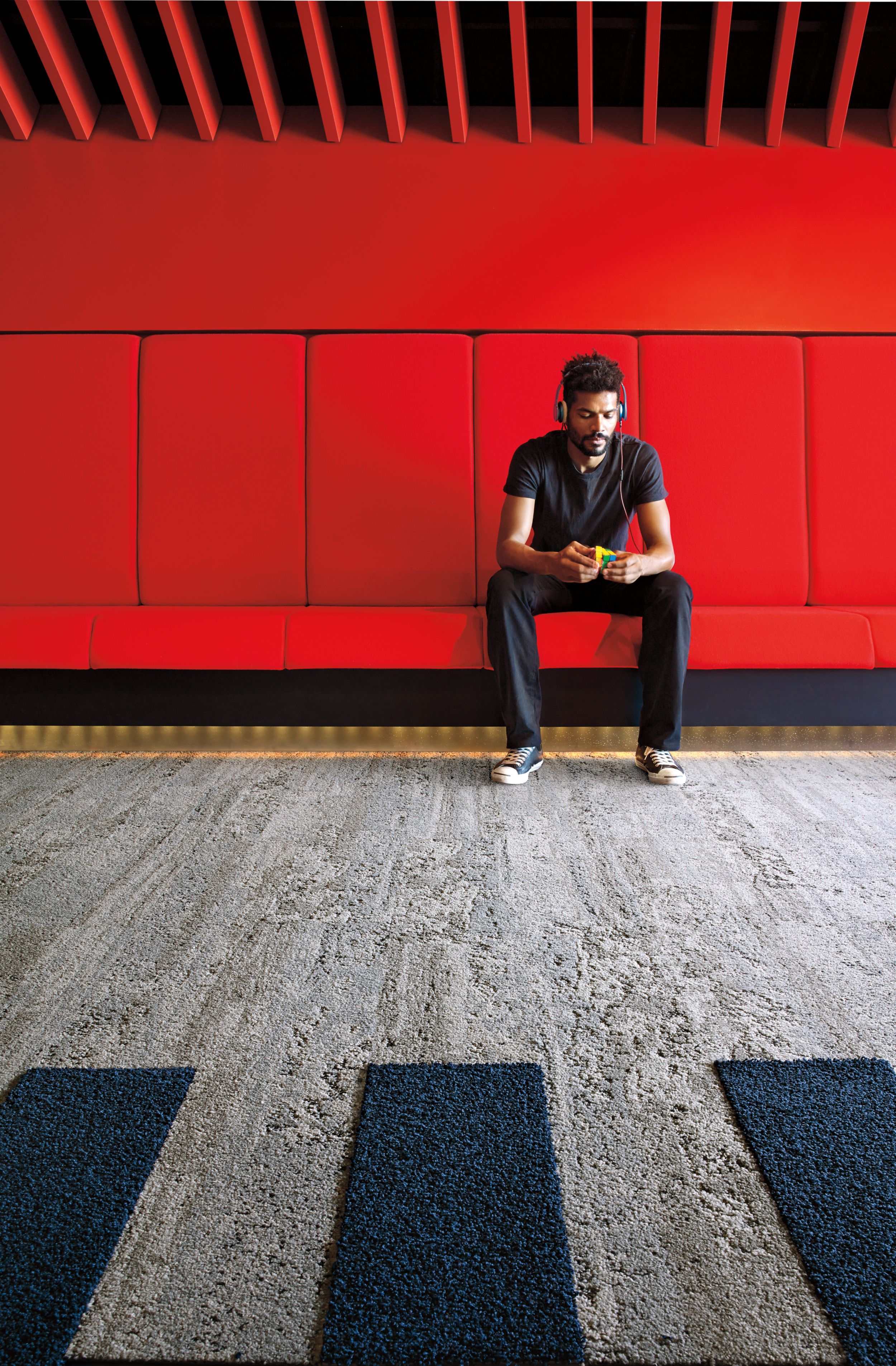 Interface HN810 plank carpet tile in waiting area with red bench and wall and man listening to music imagen número 3