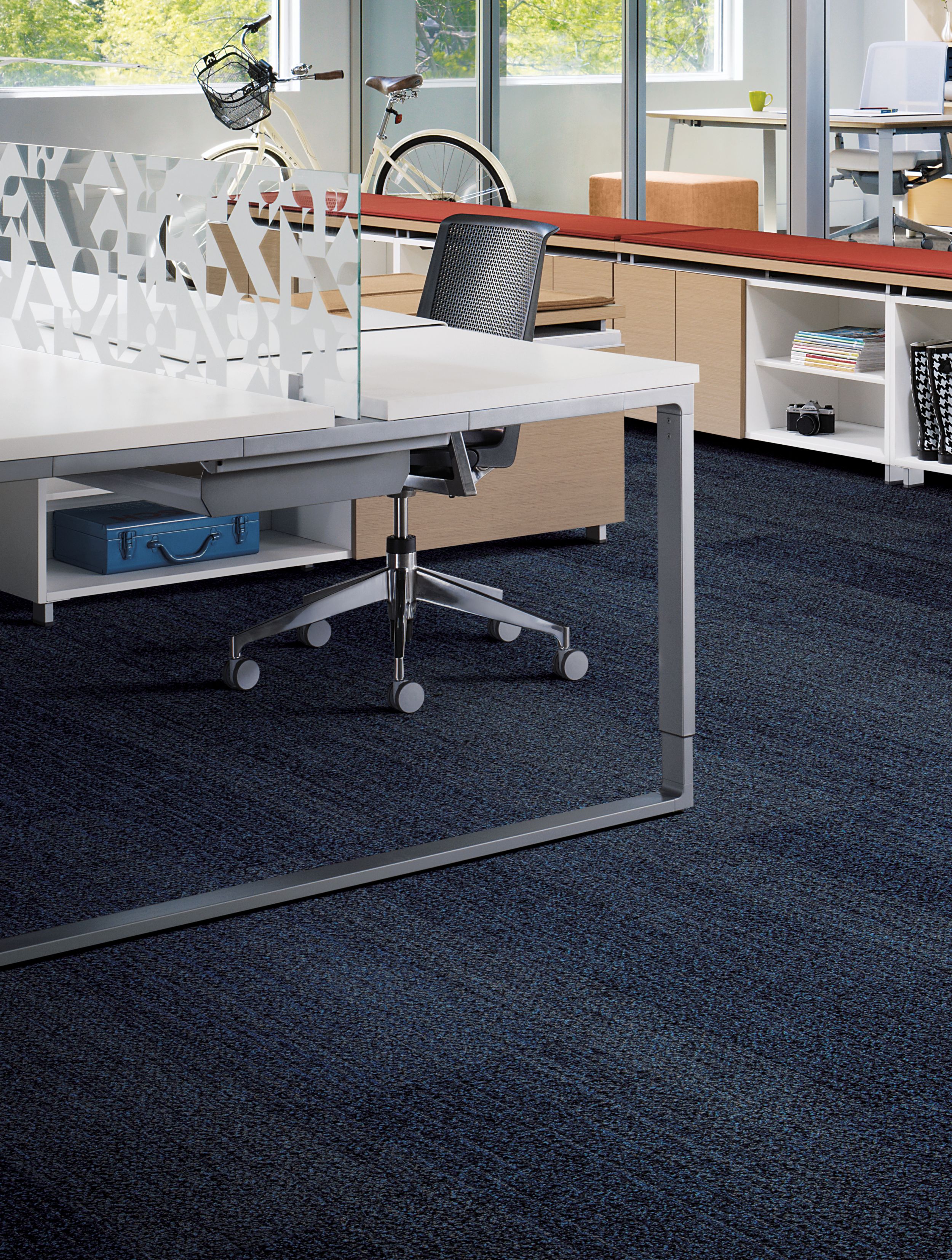 Interface Harmonize plank carpet tiles in workspace area with open desk, red covering on shelf and bike in background image number 6