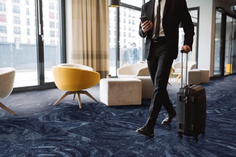 Interface Head Over Heels M1048 carpet tile in hotel lobby with man rolling suitcase image number 10