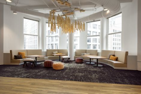 Interface Heartthrob carpet tile in common space with booths in half circle and highrise office building in background