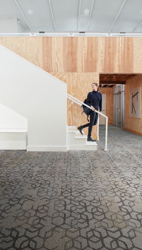 Interface Honey Do carpet tile with woman walking down open stairway and looking back