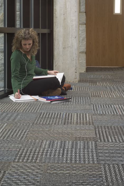 Interface Cotswold II carpet tile in corridor with woman seated and studying