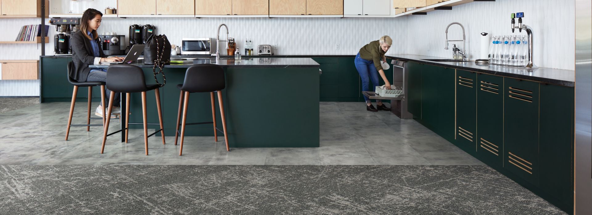 Interface Ice Breaker carpet tile and Textured Stones LVT in kitchen area with women lodaing dish washer and women working on computer