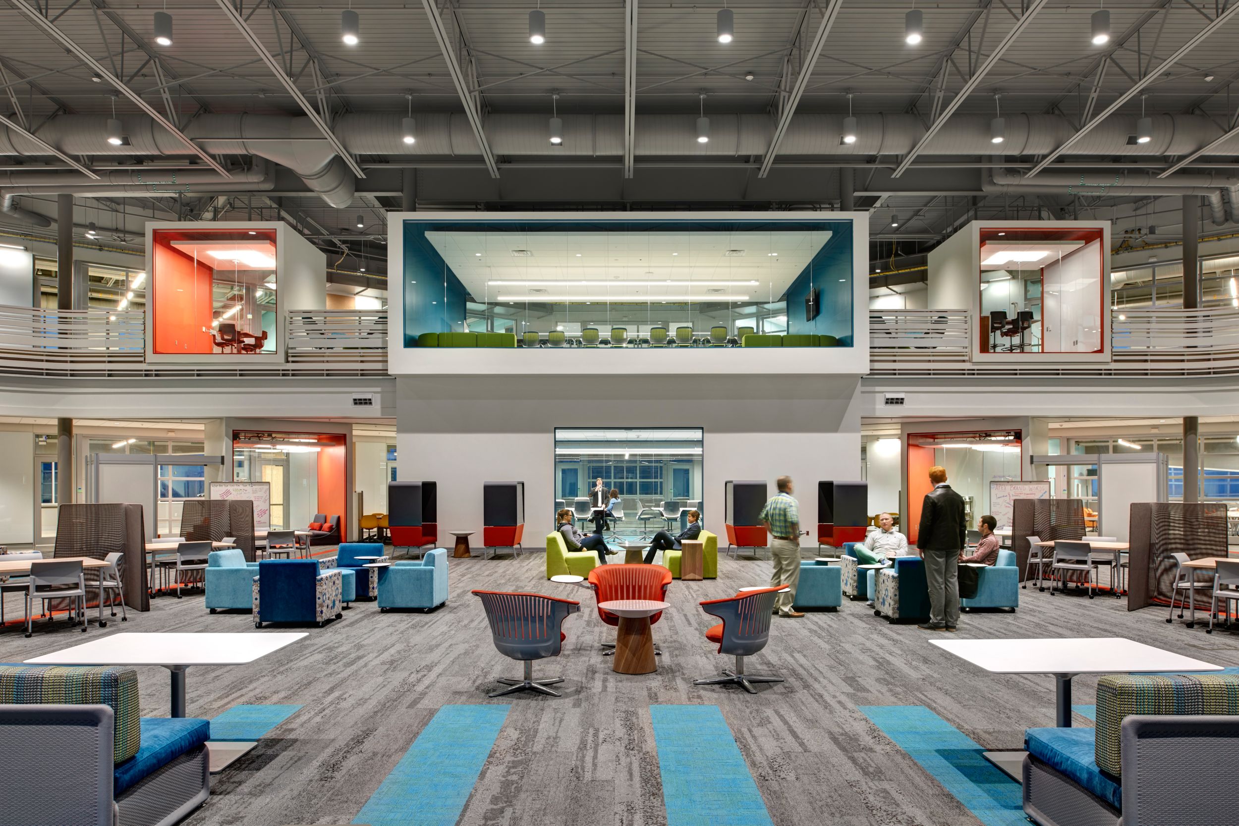 Interface HN810, HN820 and HN850 plank carpet tiles in first floor view of open office space with employees working and glass meetings rooms in the back on second floor image number 10