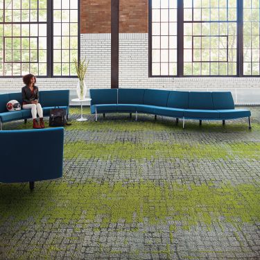 Interface Moss and Moss in Stone carpet tile in seating area with blue couches and women seated