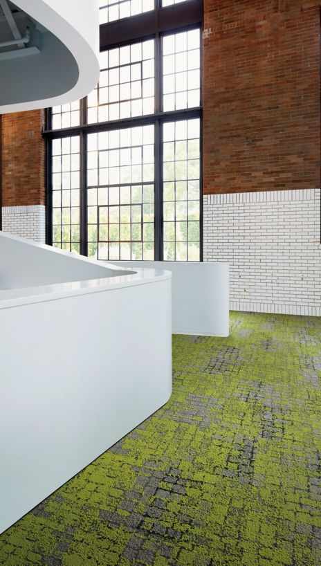 Interface Moss carpet tile in open area with brick wall and glass window in background