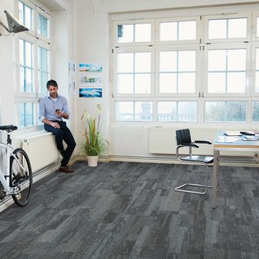 Interface Naturally Weathered plank carpet tile in office space with man looking at phone on window sill imagen número 1