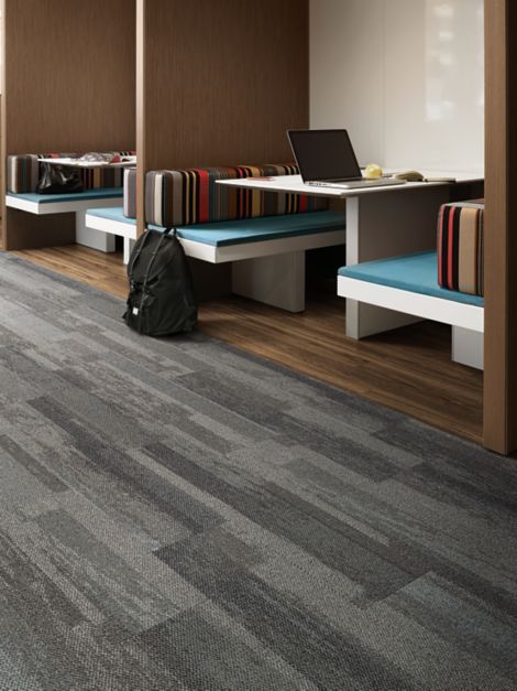 Interface Naturally Weathered plank carpet tile and Natural Woodgrains LVT in office with laptop and backpack in booth seating