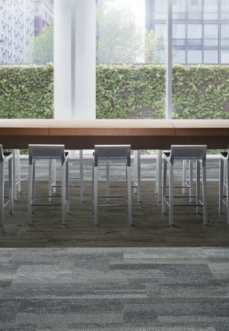 Interface Naturally Weathered plank carpet tile and Natural Woodgrains LVT with hightop meeting table and glass windows showing ivy covered wall