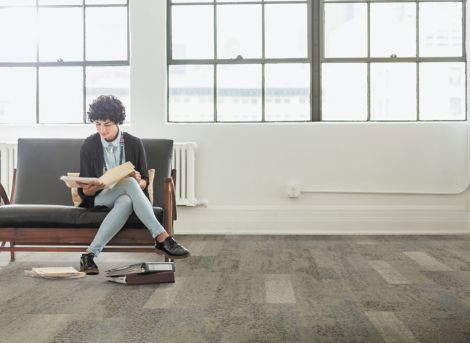Interface Nature's Course plank carpet tile in lobby with woman sitting on bench reading a book image number 3