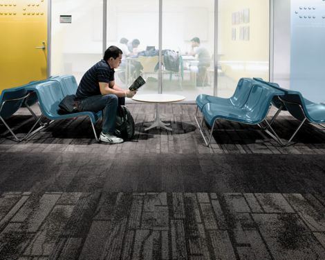 Interface Neighborhood Blocks and Neighborhood Smooth plank carpet tile in public education space with man reading a book on blue chair