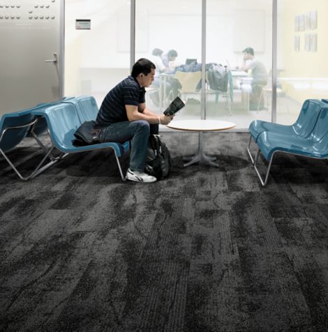 Interface Neighborhood Smooth plank carpet tile in public education space with man reading a book on blue chair imagen número 2