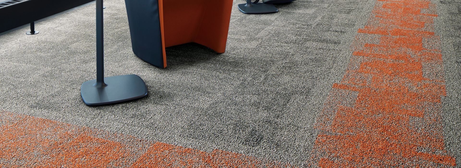 Interface Open Air 404 carpet tile in corner space with open cement ceiling and orange chairs