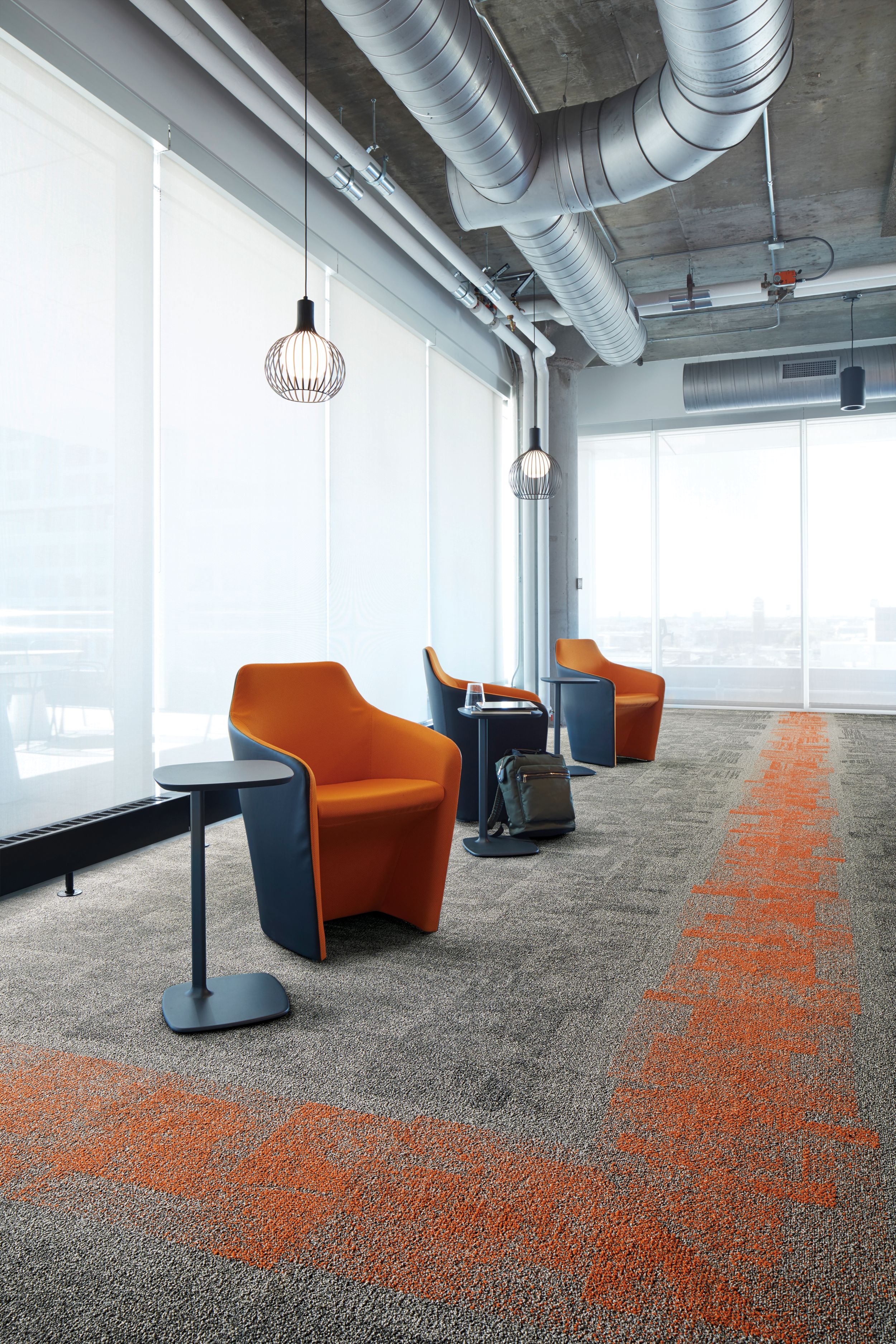 Interface Open Air 404 carpet tile in corner space with open cement ceiling and orange chairs image number 3