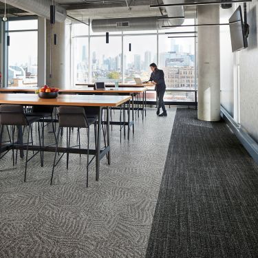 Interface Open Air 401 and 422 carpet tile in dining area with wood tables and man with laptop image number 1