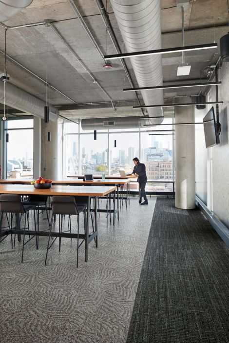 Interface Open Air 401 and 422 carpet tile in dining area with wood tables and man with laptop image number 2