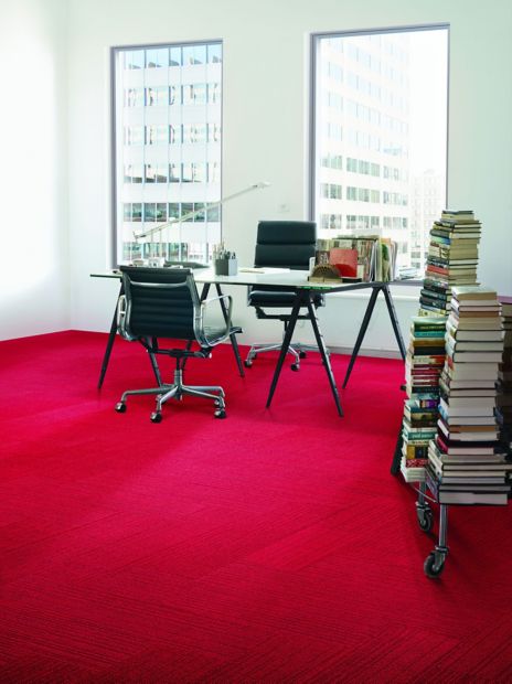 Interface On Line plank carpet tile in space with desk and stacks of books against wall