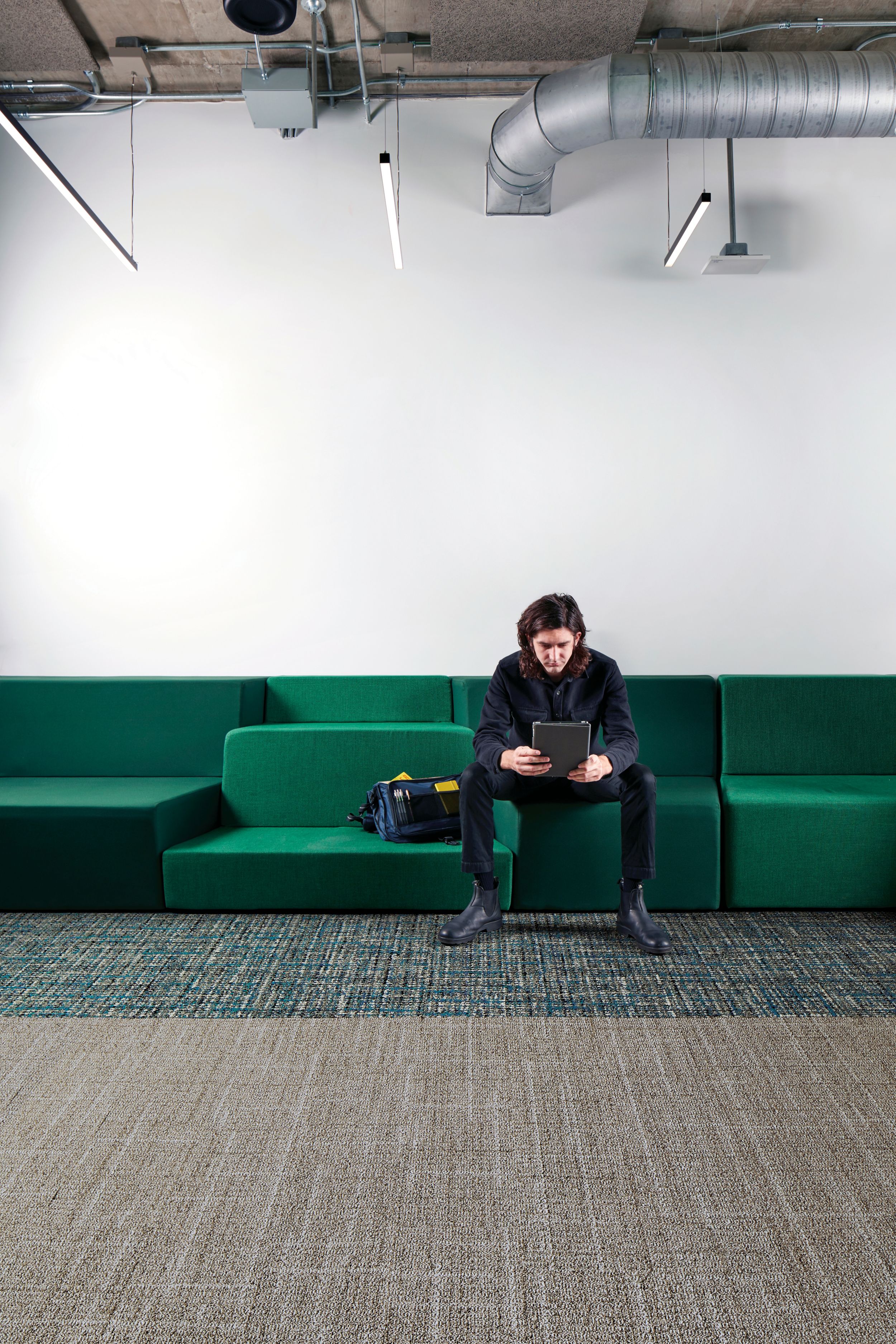 Interface Open Air 401 plank carpet tile with man working on tablet sitting on long green couch numéro d’image 1
