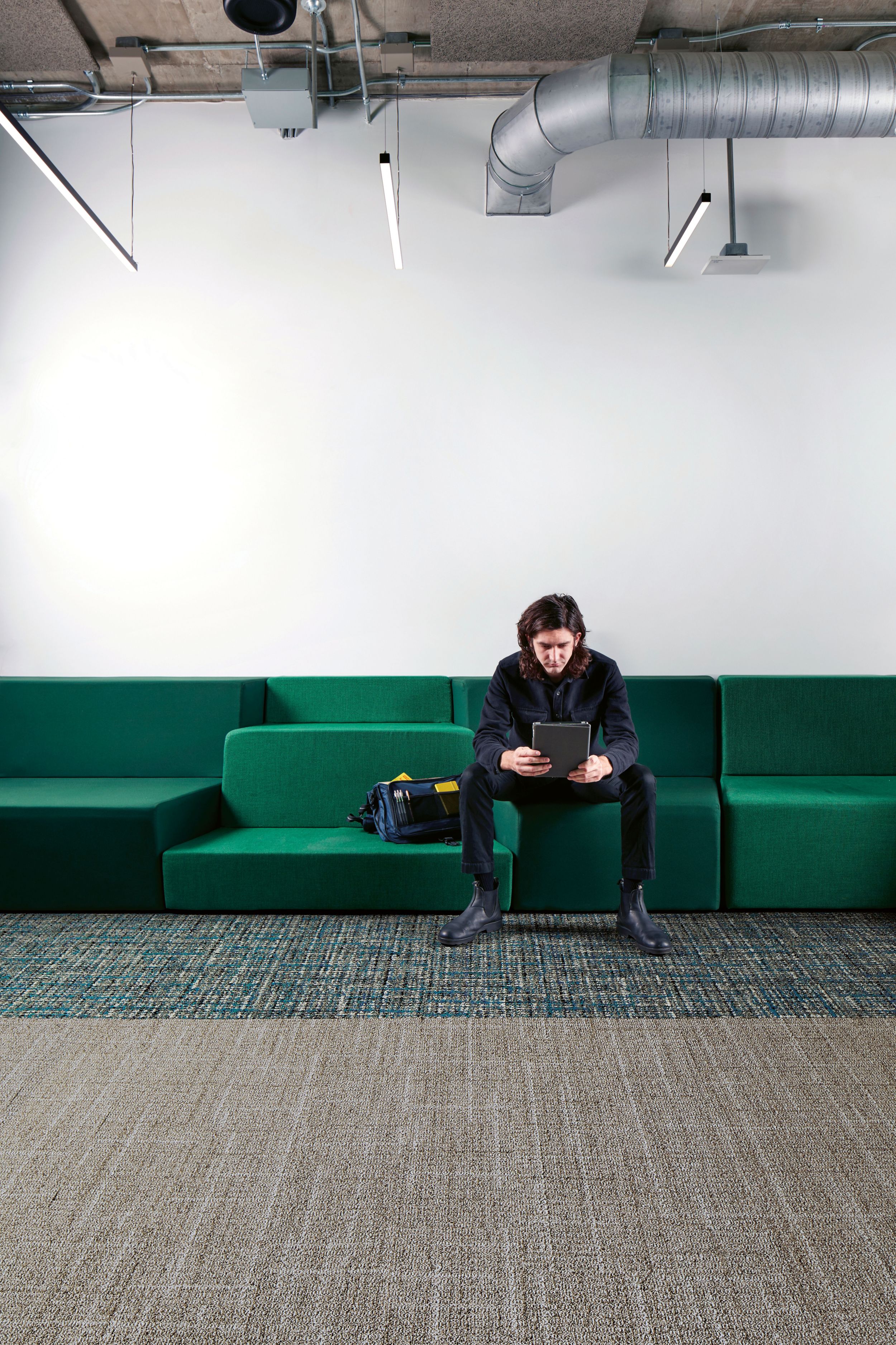 Interface Open Air 401 plank carpet tile with man working on tablet sitting on long green couch image number 1