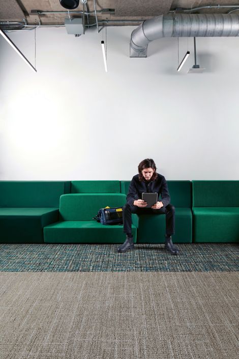 Interface Open Air 401 plank carpet tile with man working on tablet sitting on long green couch image number 3