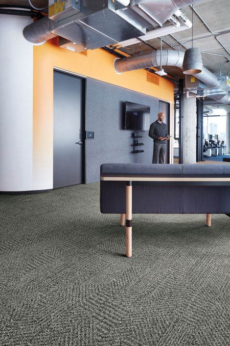 Interface Open Air 407 plank carpet tile with grey fabric couch and man standing in the background image number 4
