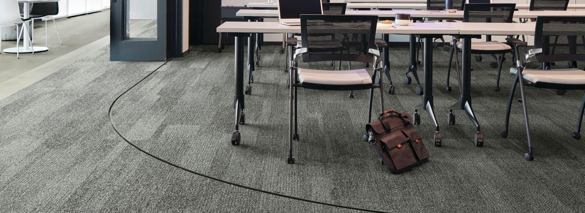 Interface Open Air 410 plank carpet tile in open conference room with satchel leaning on chair imagen número 1