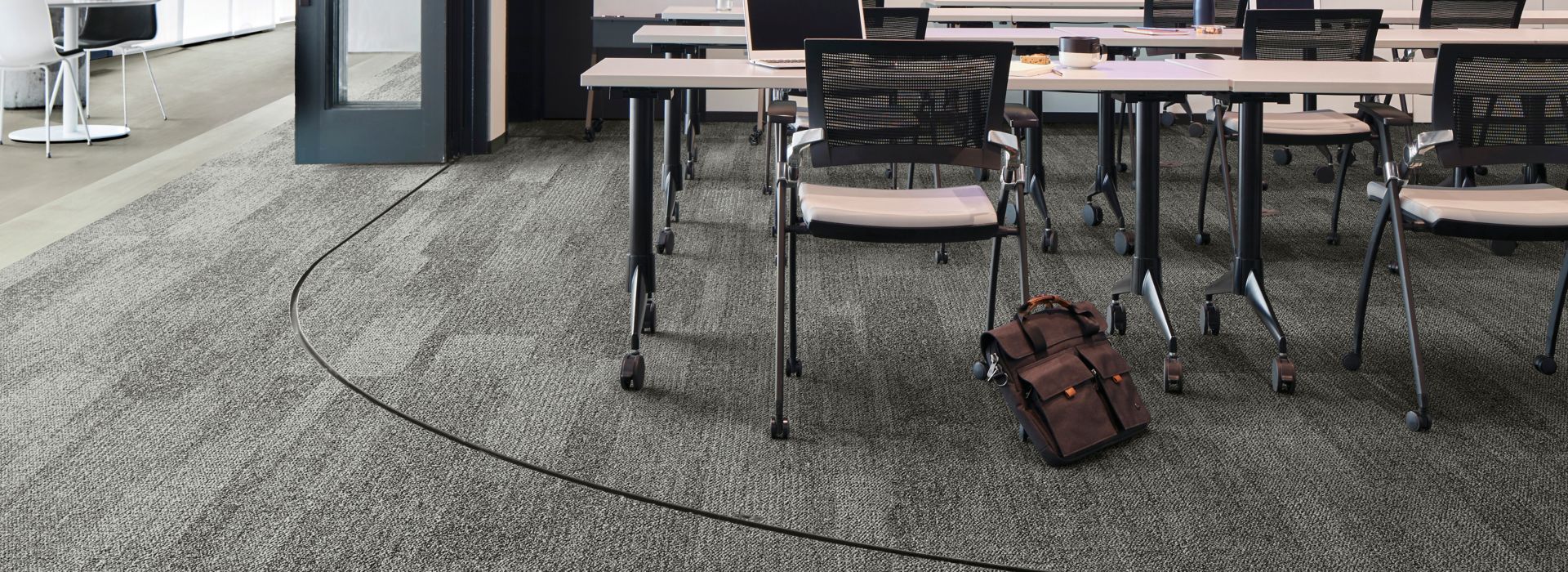 Interface Open Air 410 plank carpet tile in open conference room with satchel leaning on chair