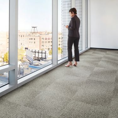 Interface Open Air 416 carpet tile with woman staring out of corner floor to ceiling window
