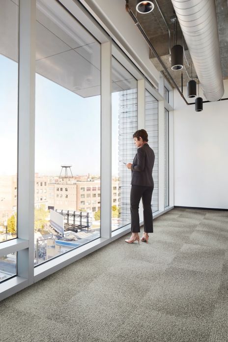 Interface Open Air 416 carpet tile with woman staring out of corner floor to ceiling window