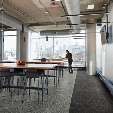 Interface Open Air 422 carpet tile in dining area with open wood tables and man working on laptop at the end image number 1