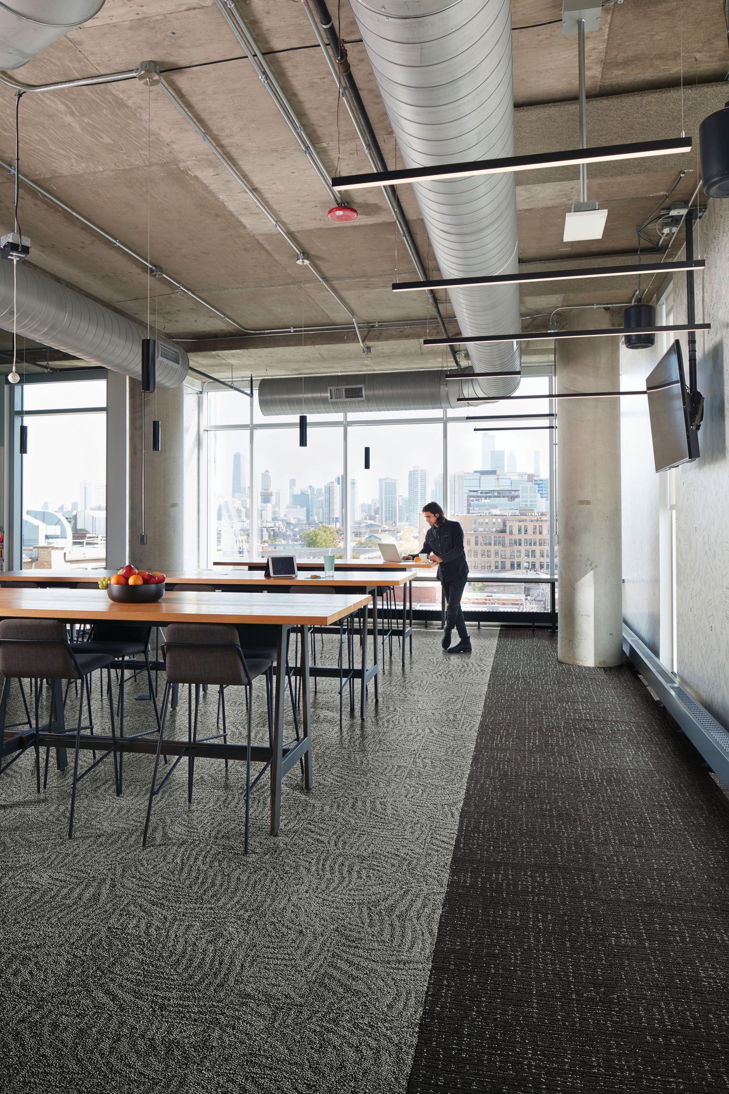 Interface Open Air 422 carpet tile in dining area with open wood tables and man working on laptop at the end image number 2