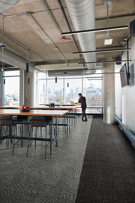 Interface Open Air 422 carpet tile in dining area with open wood tables and man working on laptop at the end imagen número 2