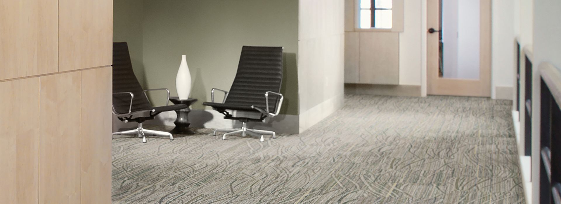 Interface Prairie Grass Loop carpet tile in corridor with seating area on side