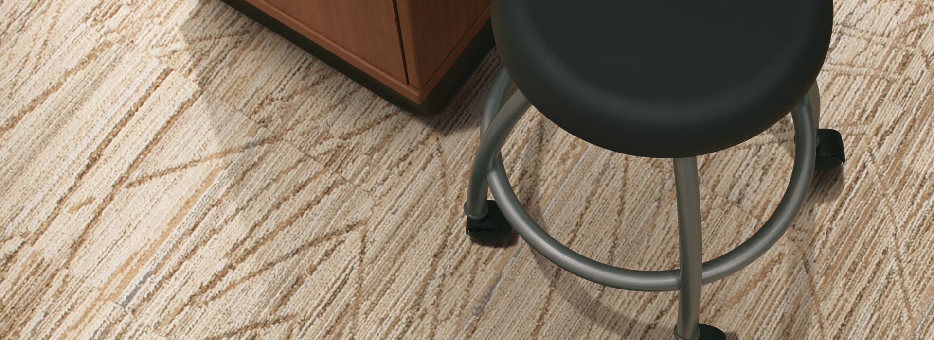 Interface Prairie Grass carpet tile in close up view with stool and cabinet